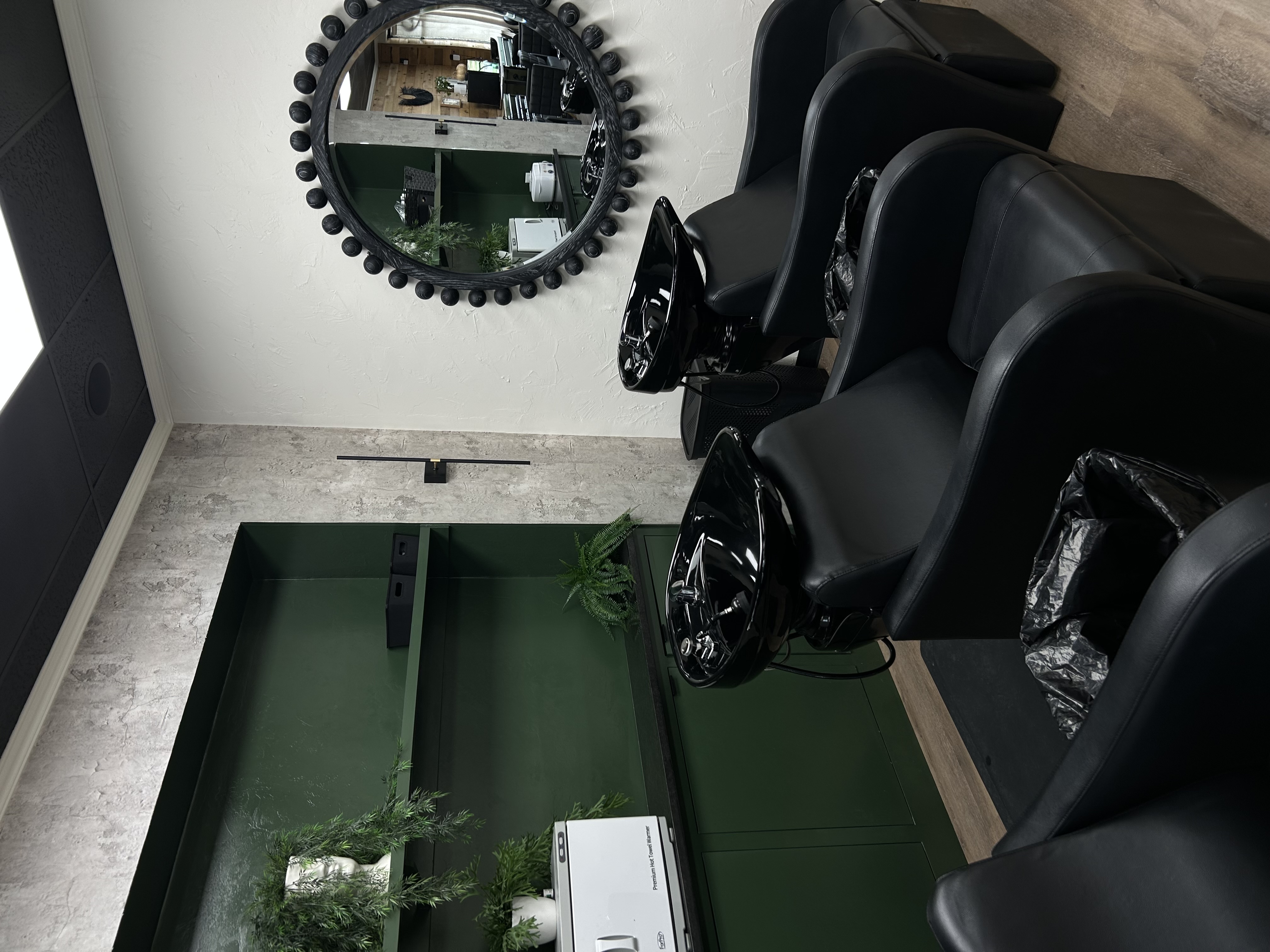 Hair washing stations with black shampoo bowls and modern green decor at The Hair Collective salon in Oklahoma City