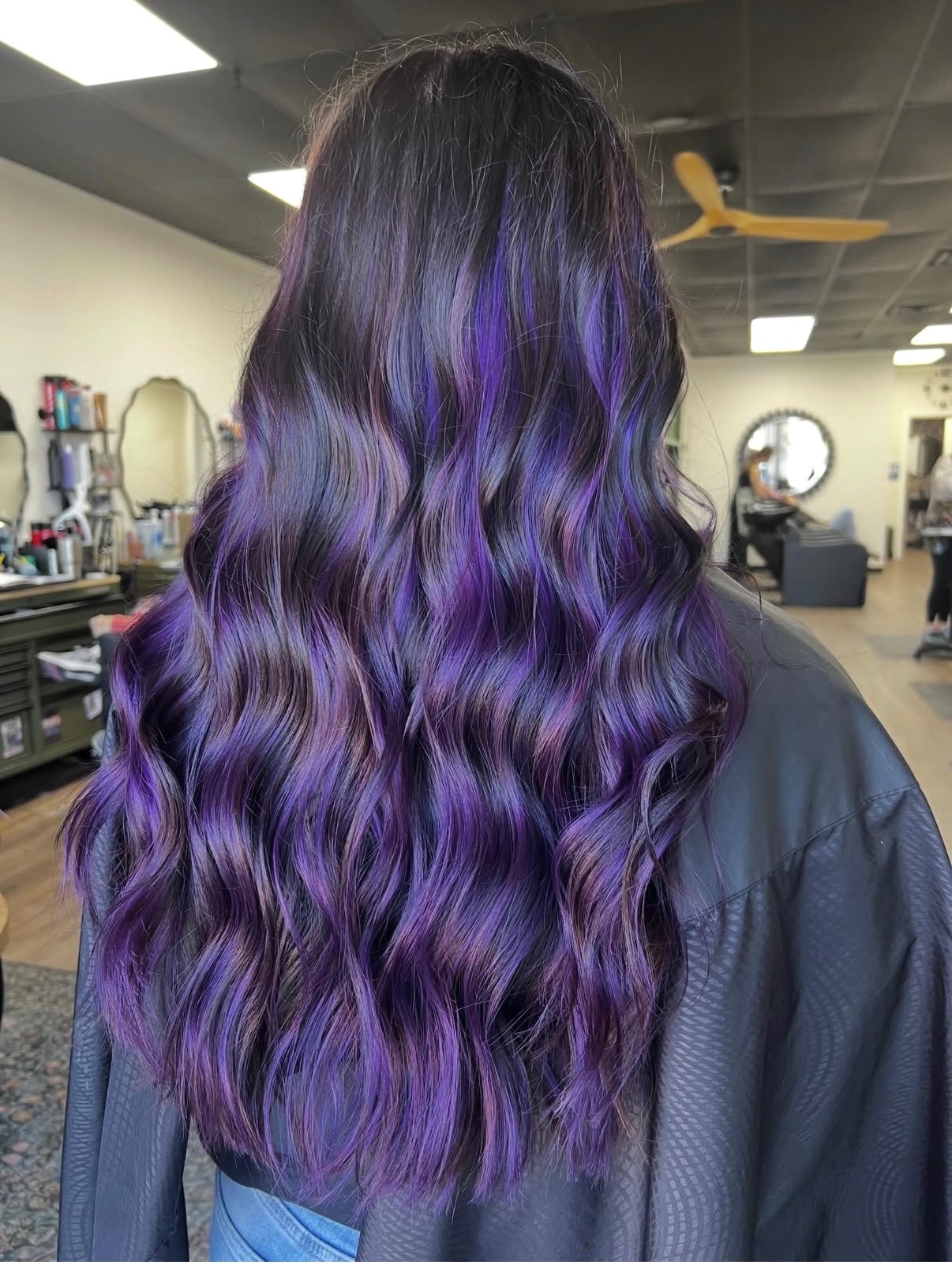 Purple balayage on dark hair styled in waves at Oklahoma City hair salon The Hair Collective