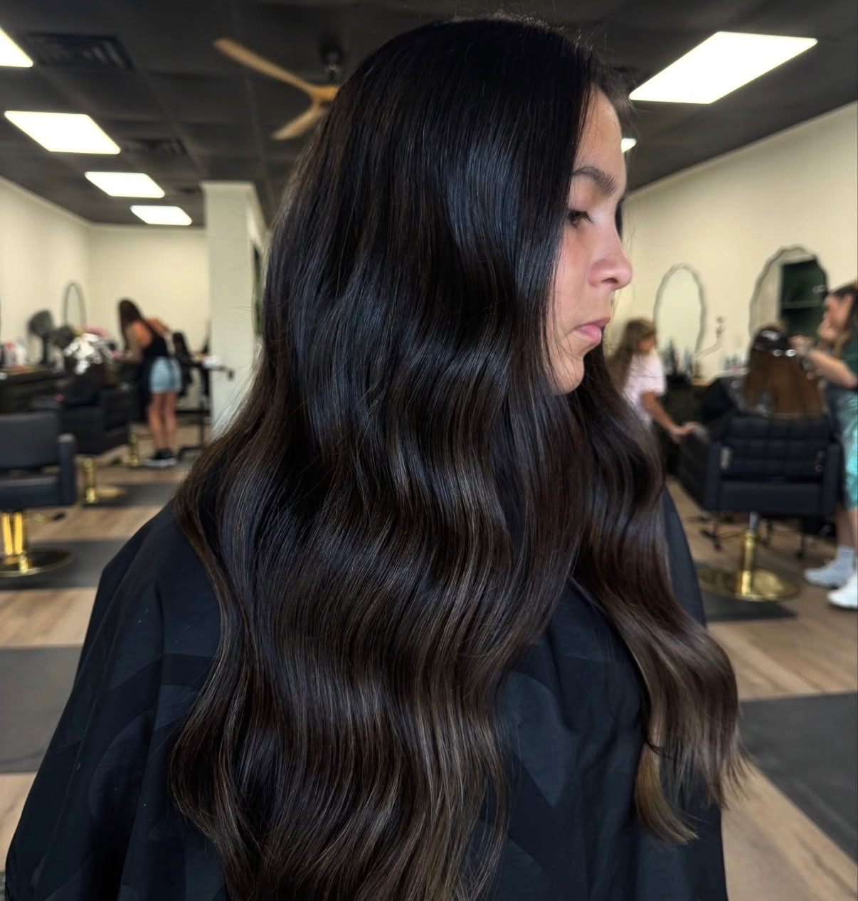 Glossy dark brunette hair with subtle dimension styled in waves at The Hair Collective salon Oklahoma City